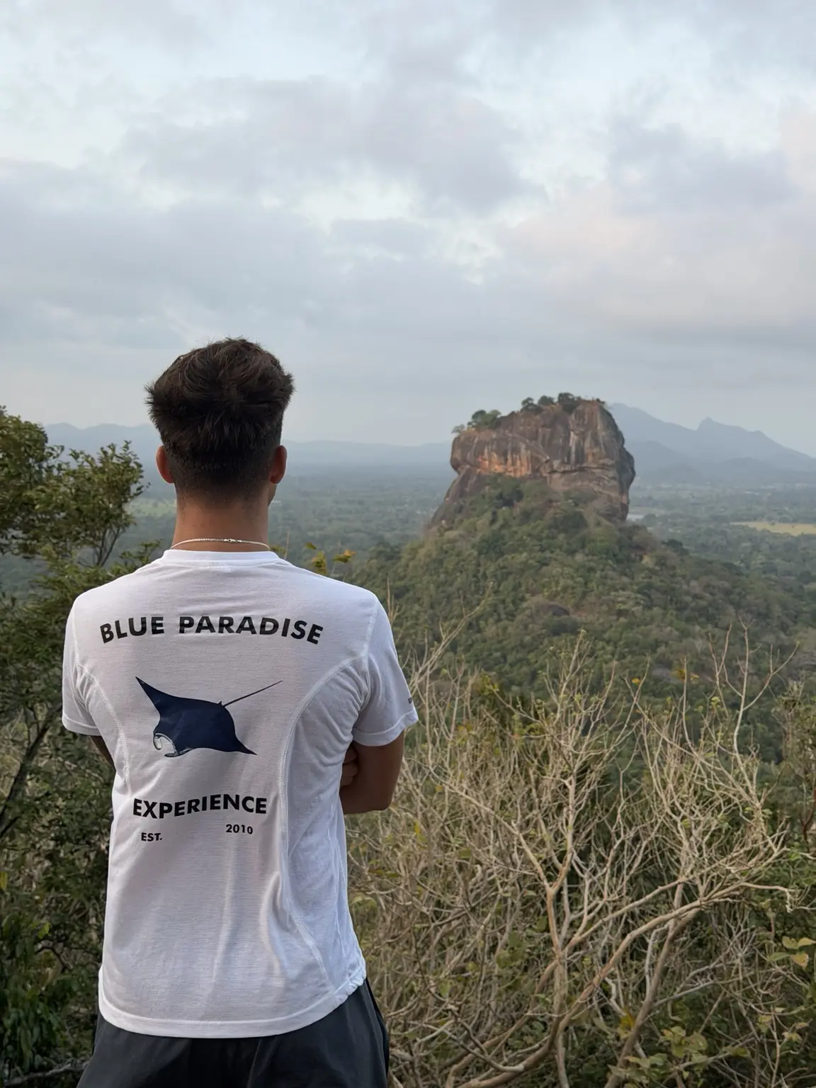 Viajero con camiseta de Blue Paradise Experience mirando la roca de Sigiriya